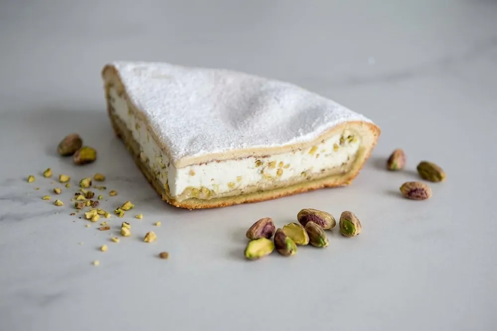 Fetta di torta di ricotta al pistacchio spolverata di zucchero a velo